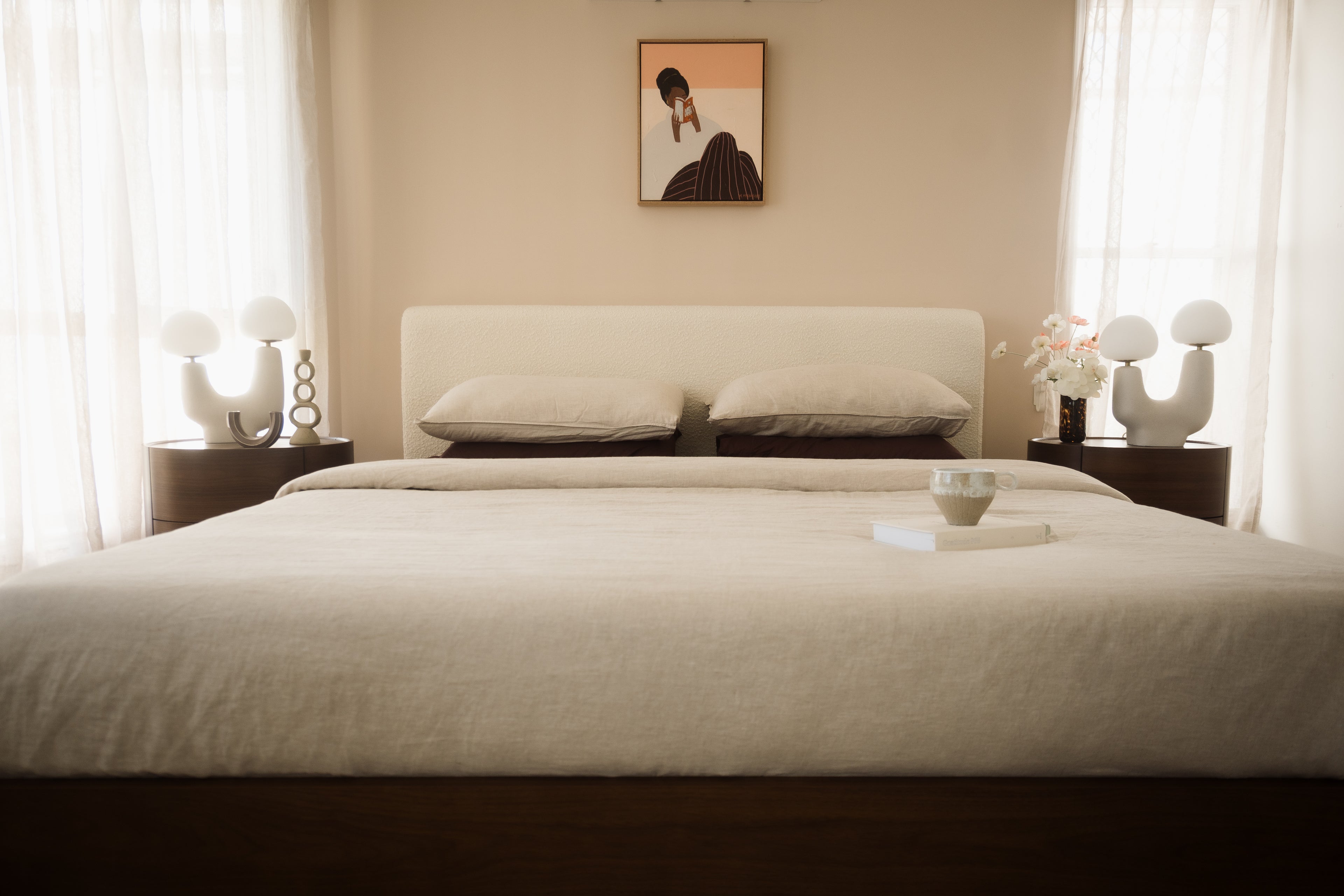 Neatly made bed in a bedroom with two nightstands and a framed picture on the wall.